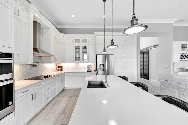 9378 Orchid Cove Cir, Vero Beach, FL 32963 - kitchen featuring crown molding, a sink, stainless steel appliances, light countertops, and wall chimney exhaust hood