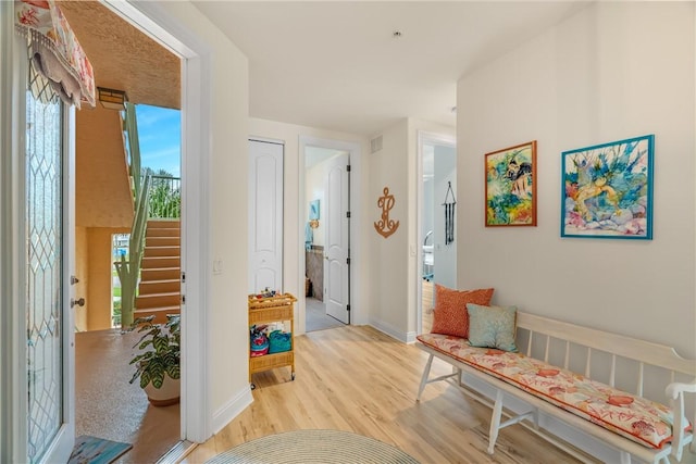 interior space featuring visible vents, baseboards, stairway, and light wood finished floors