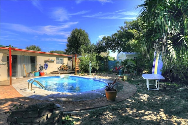 view of swimming pool with a patio, fence, a fenced in pool, and an outdoor structure