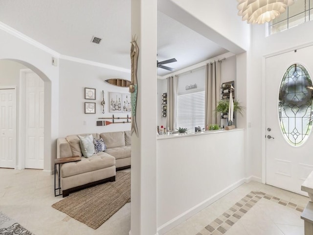 tiled foyer entrance with ceiling fan and ornamental molding