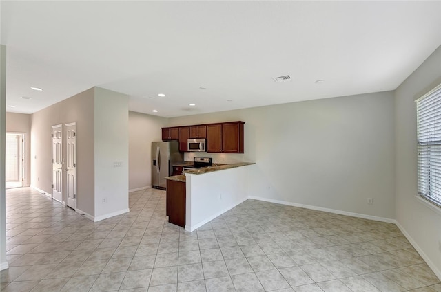 kitchen featuring kitchen peninsula, light stone countertops, light tile patterned floors, and appliances with stainless steel finishes