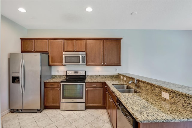 1081 Normandie Way, Vero Beach, FL 32960 - kitchen with appliances with stainless steel finishes, a peninsula, light stone countertops, light tile patterned floors, and brown cabinetry
