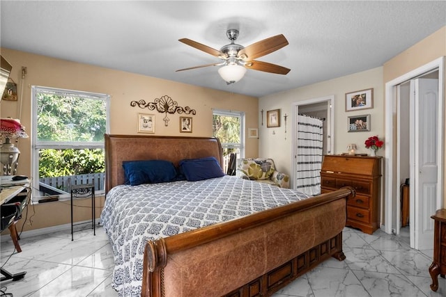 bedroom featuring a textured ceiling, ceiling fan, and multiple windows