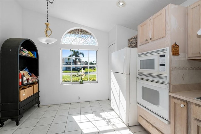 kitchen with white appliances, light brown cabinets, a healthy amount of sunlight, hanging light fixtures, and light tile patterned flooring