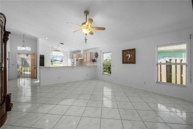 unfurnished living room with lofted ceiling, light tile patterned floors, a healthy amount of sunlight, and ceiling fan with notable chandelier