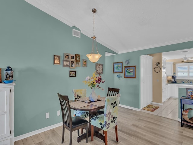 dining space with ornamental molding, lofted ceiling, sink, and light hardwood / wood-style floors