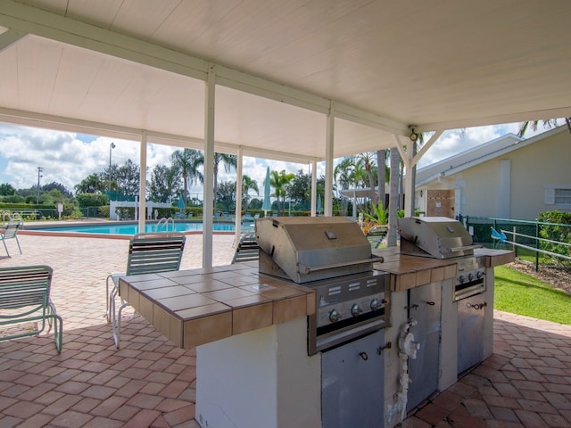 view of patio / terrace featuring a fenced in pool, a grill, and exterior kitchen