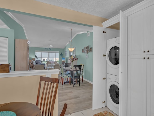 washroom with ceiling fan, a textured ceiling, stacked washer / dryer, light hardwood / wood-style flooring, and crown molding