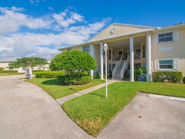 greek revival inspired property with a front yard and a porch