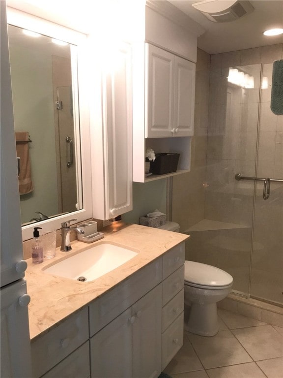 bathroom with walk in shower, vanity, toilet, and tile patterned flooring