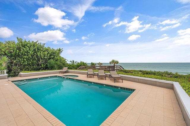 swimming pool featuring an in-ground hot tub, a water view, and a patio