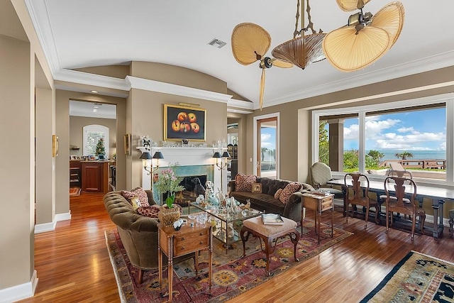 living room featuring wood finished floors, a fireplace, crown molding, and vaulted ceiling