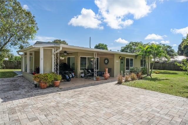 rear view of property with ceiling fan and a lawn