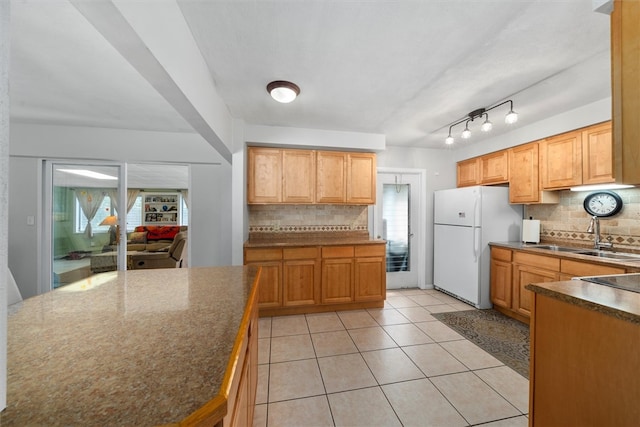 kitchen featuring decorative backsplash, sink, white fridge, and light tile patterned flooring