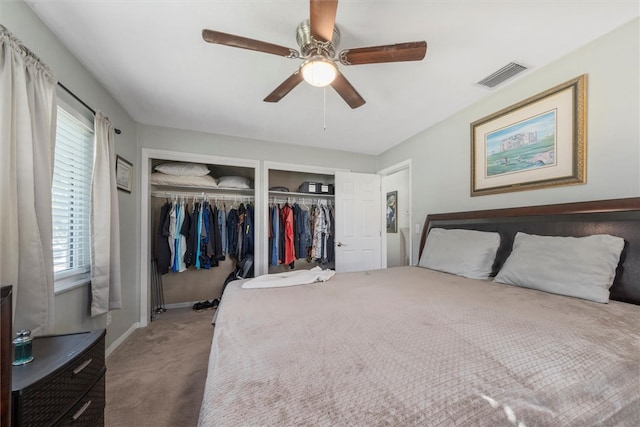 bedroom featuring ceiling fan, carpet floors, and multiple closets