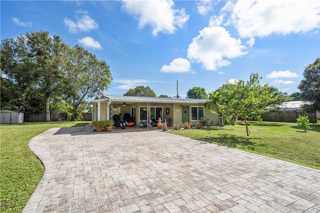 ranch-style home with a front yard, a porch, a shed, and ceiling fan