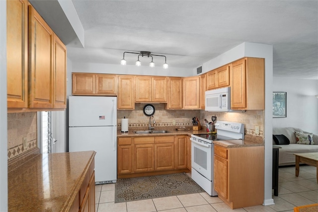 kitchen featuring backsplash, sink, light tile patterned floors, and white appliances