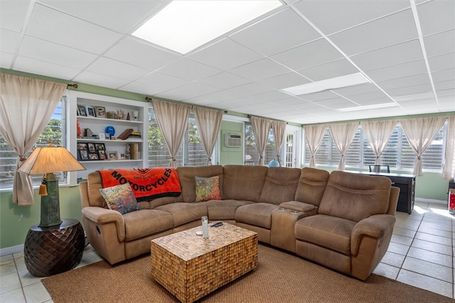 tiled living room with a wall mounted AC and a drop ceiling