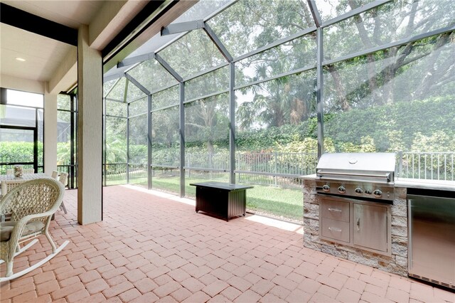 view of patio / terrace with glass enclosure, exterior kitchen, and a grill