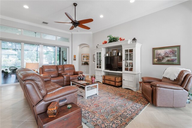 tiled living room with a towering ceiling, ceiling fan, and crown molding