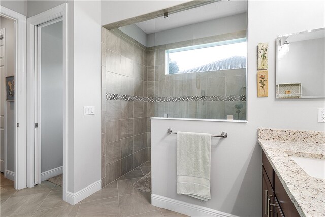 bathroom featuring tile patterned flooring, vanity, and tiled shower