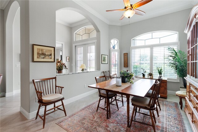 tiled dining space with a towering ceiling, ceiling fan, and ornamental molding