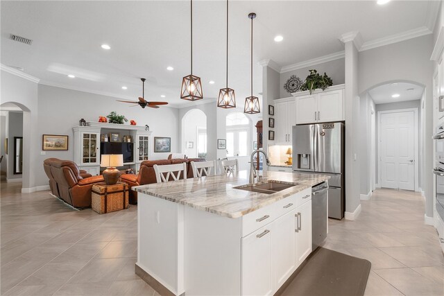 kitchen with white cabinetry, sink, light stone counters, appliances with stainless steel finishes, and an island with sink