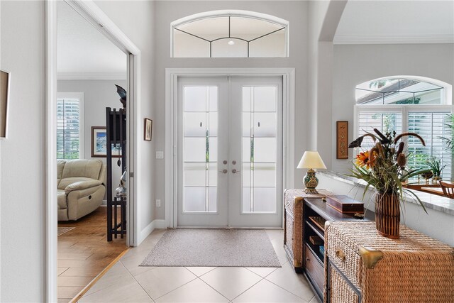 entrance foyer featuring light hardwood / wood-style floors, plenty of natural light, french doors, and crown molding