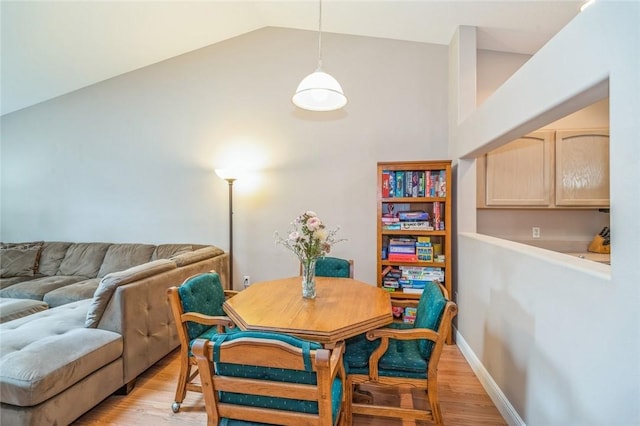 dining room featuring vaulted ceiling and light hardwood / wood-style flooring