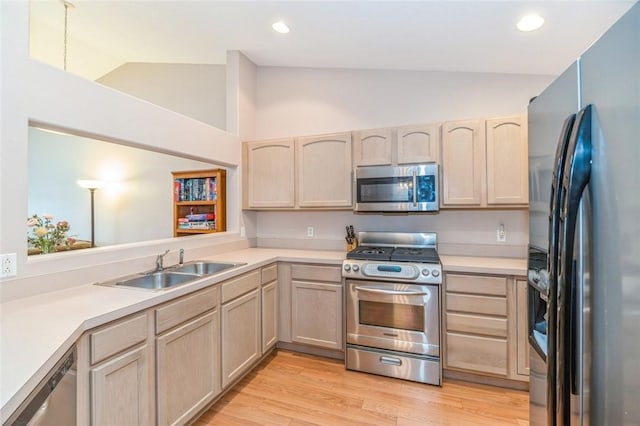 kitchen with sink, light brown cabinets, lofted ceiling, and appliances with stainless steel finishes