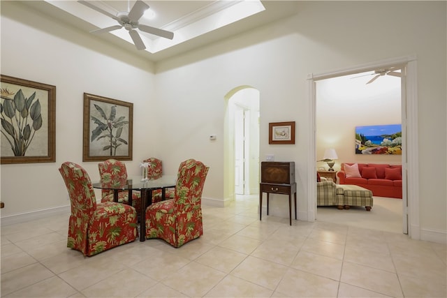 tiled dining space with ceiling fan and crown molding