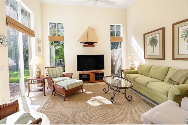 living room featuring a high ceiling, ceiling fan, and crown molding