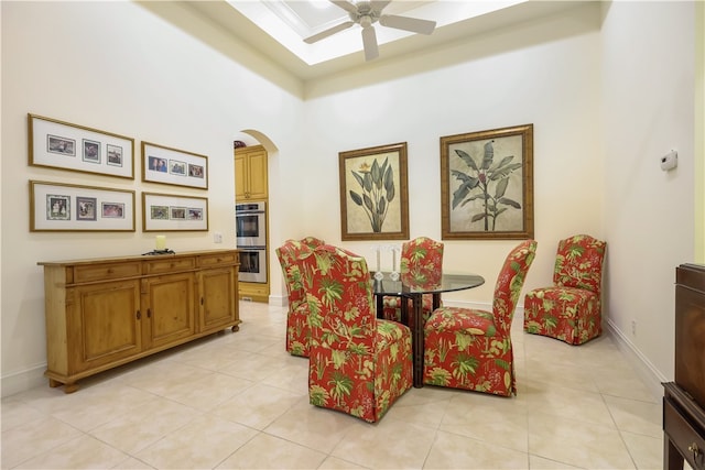 tiled dining room featuring ceiling fan and a high ceiling