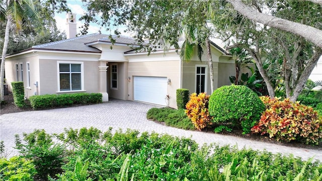1632 Weybridge Cir, Vero Beach, FL 32963 - view of front of home with an attached garage, a chimney, stucco siding, and decorative driveway