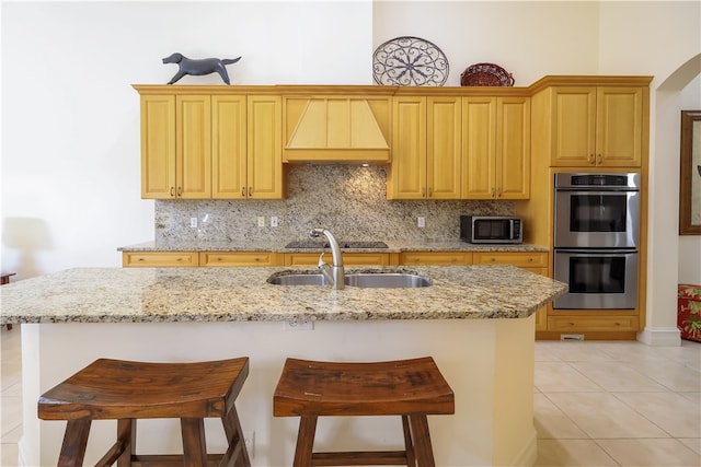 kitchen featuring appliances with stainless steel finishes, a breakfast bar area, light tile patterned floors, backsplash, and custom exhaust hood