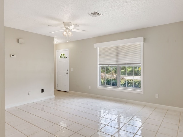 tiled empty room featuring a textured ceiling and ceiling fan