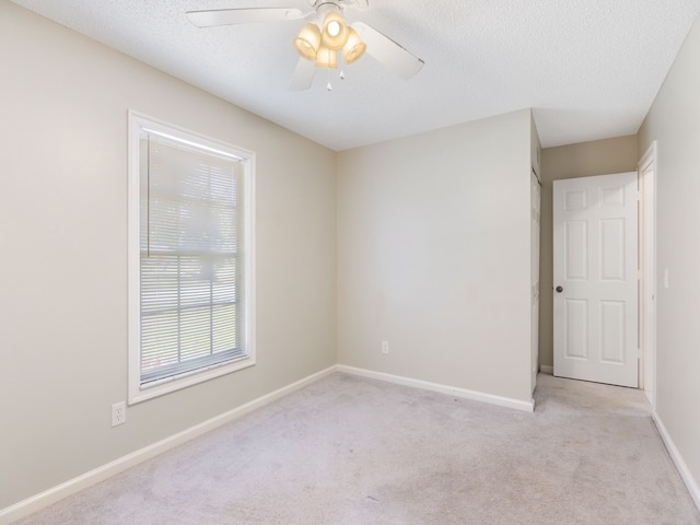 spare room featuring a textured ceiling, light carpet, and ceiling fan