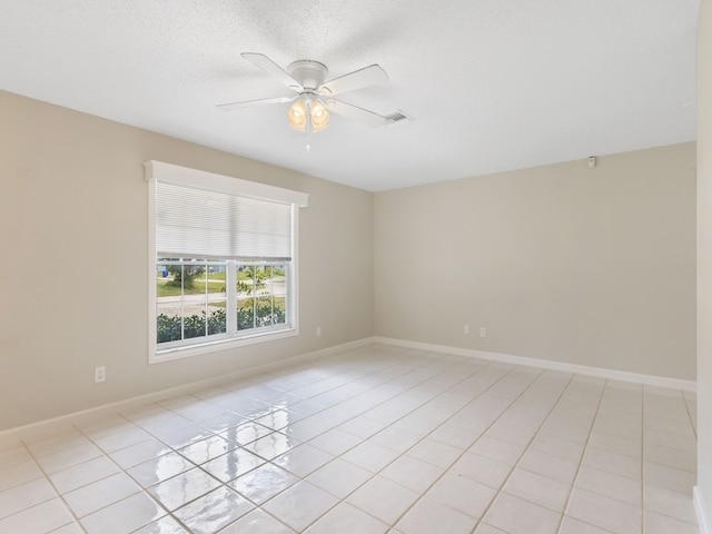 tiled spare room with a textured ceiling and ceiling fan