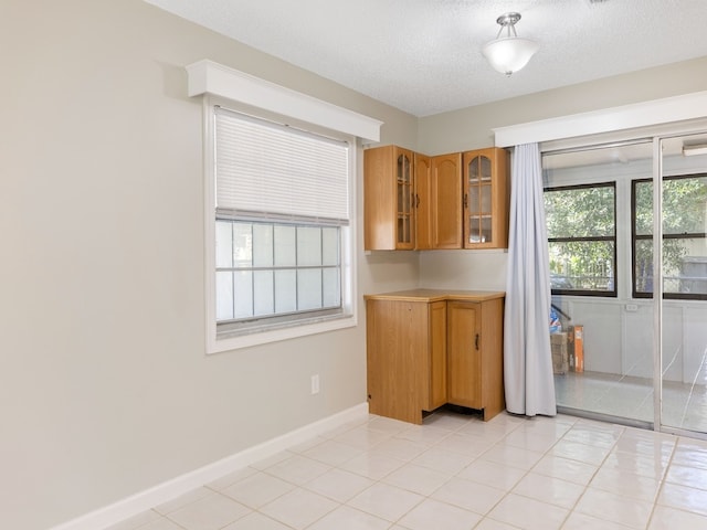 kitchen with a textured ceiling, a wealth of natural light, and light tile patterned flooring