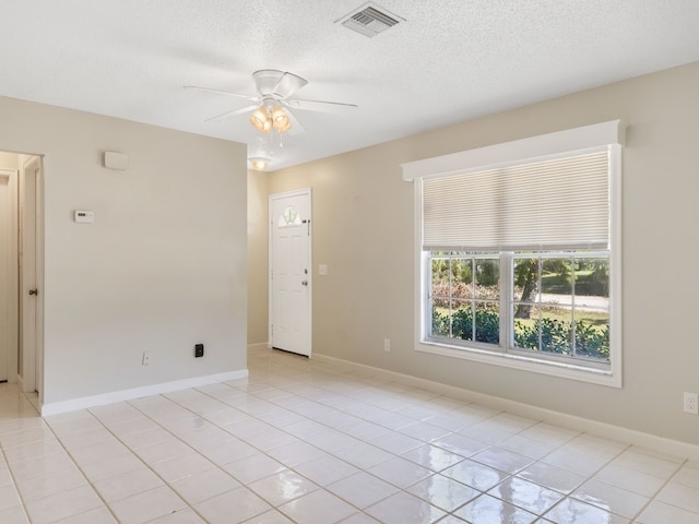 spare room featuring a textured ceiling, light tile patterned floors, and ceiling fan