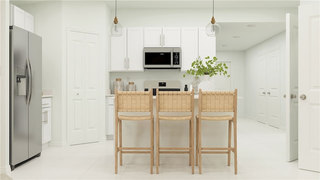 kitchen with stainless steel appliances, white cabinets, a breakfast bar, and decorative light fixtures