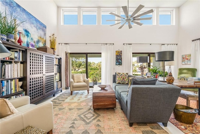 living room with plenty of natural light, a ceiling fan, and a towering ceiling