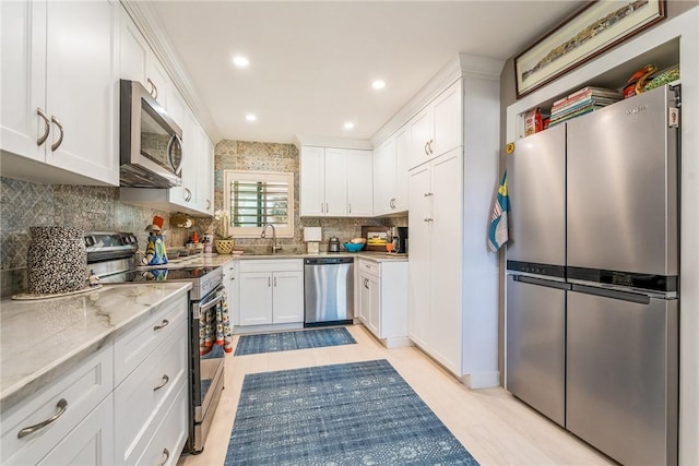 kitchen featuring decorative backsplash, white cabinets, stainless steel appliances, and a sink