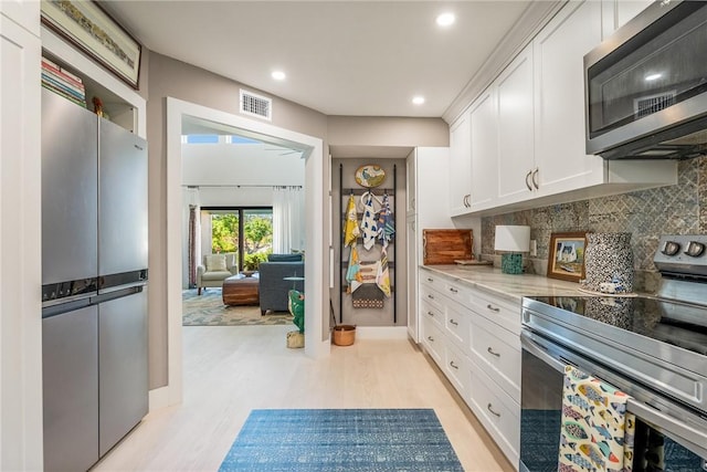 kitchen with visible vents, white cabinetry, appliances with stainless steel finishes, decorative backsplash, and light stone countertops