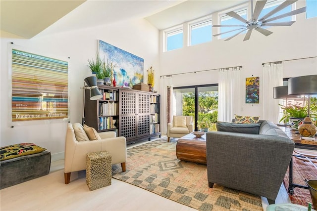 living room with wood finished floors, ceiling fan, and a towering ceiling