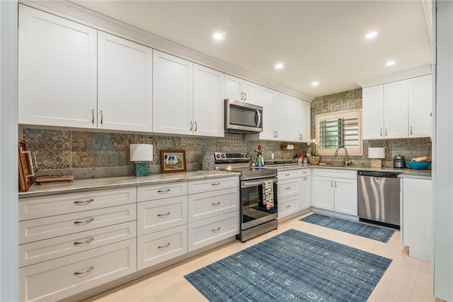 kitchen with recessed lighting, a sink, stainless steel appliances, white cabinetry, and tasteful backsplash