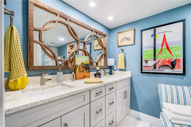 bathroom featuring a sink, baseboards, recessed lighting, and double vanity