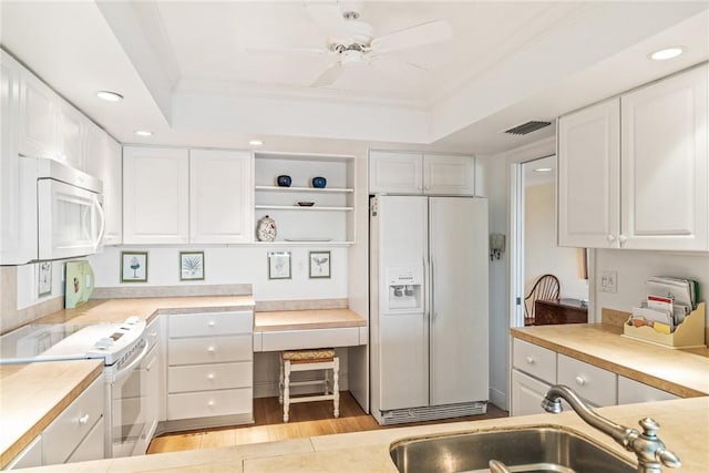 kitchen with visible vents, white cabinets, white appliances, a raised ceiling, and a sink