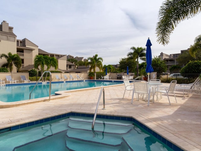 community pool featuring a patio area, a community hot tub, and fence