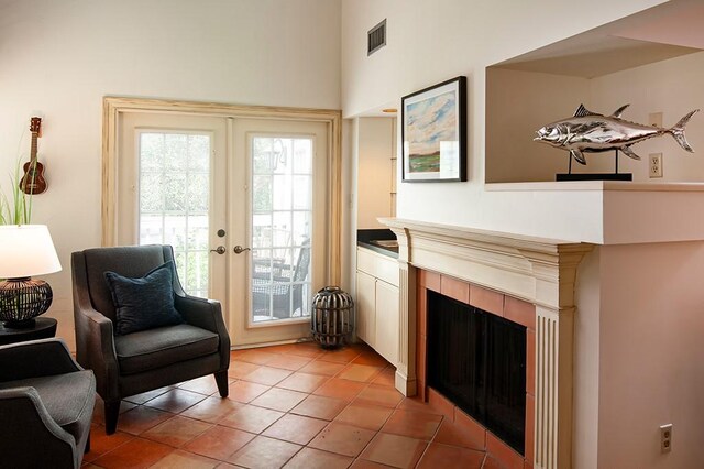 110 Amy Ann Ln, Vero Beach, FL 32963 - sitting room featuring a tiled fireplace, light tile patterned floors, french doors, and a high ceiling